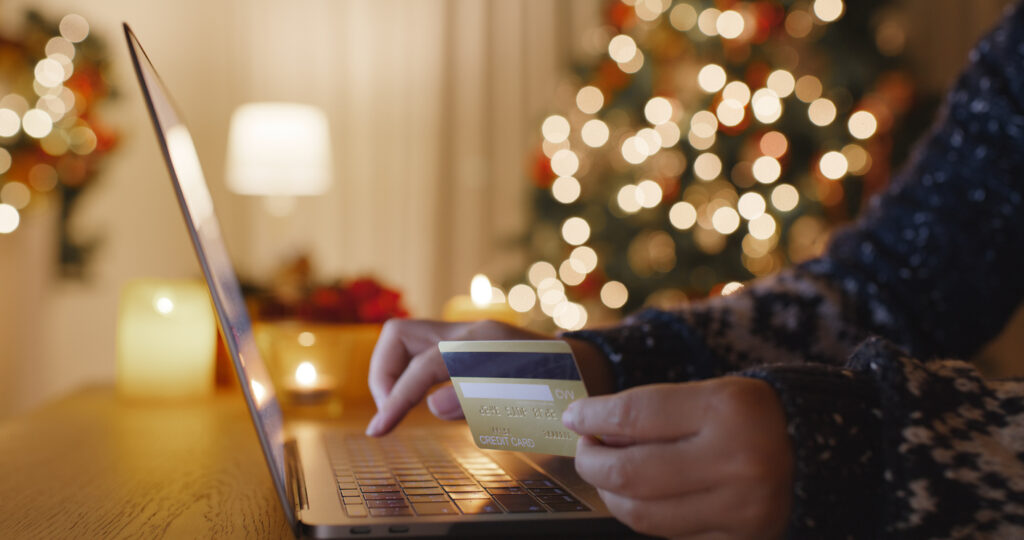 person holding a credit card with a christmas tree behind them